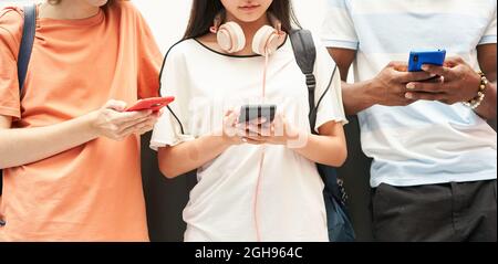 Multi-ethnic group of unrecognizable students using a smart phone. Stock Photo