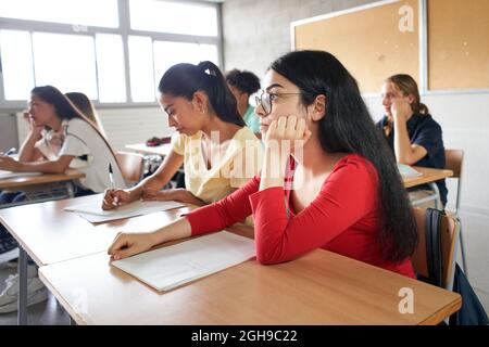 Group of students sitting in class attending to the teacher. Stock Photo
