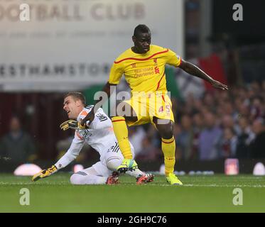 West Ham's Adrian gets caught late by Liverpool's Mario Balotelli during the Barclays Premier League match between West Ham United and Liverpool held at the Upton Park in London, England on September 20, 2014. Stock Photo