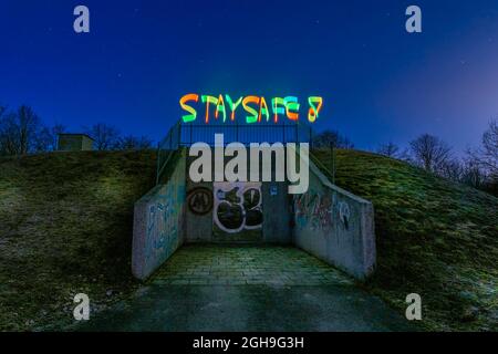 Best wishes in times of Corona and the Covid-19 virus, lightpaining at night with STAY SAFE painted colorful at the top of a bunker. Stock Photo