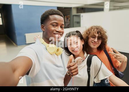 Photographic portrait of cheerful classmates at reunion taking selfie smiling at school. Stock Photo