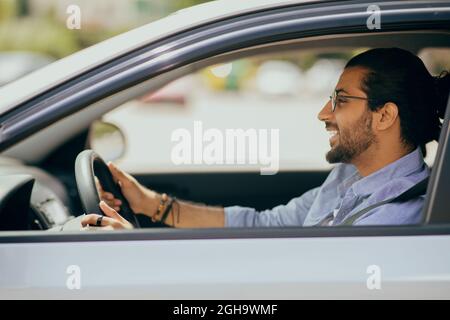 Handsome millennial arabic guy driving car, side view Stock Photo