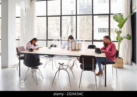 In the office. Three businesswomen work together without masks while keeping a safe distance. Stock Photo