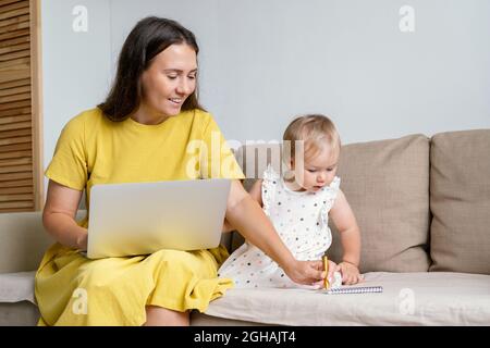 Happy mother taking notes for child while working from home. Multitasking due to maternity leave Stock Photo