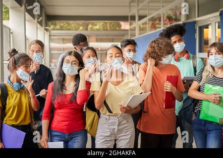 Group of students putting on or taking off their face masks. Young people of various ethnicities take safety measures against the covid virus. Back to Stock Photo