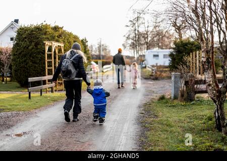 Full length rear view of mother and son holding hands while walking on road Stock Photo