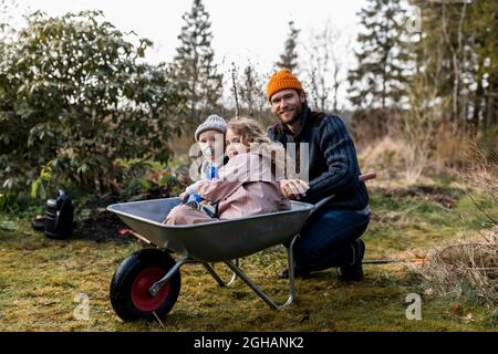 Boy And Girl Sitting In Wheelbarrow Stock Photo - Alamy