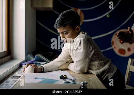 Autistic boy holding stress ball while reading book at home Stock Photo