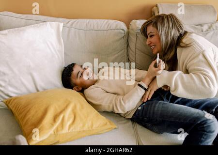 Smiling mother and son playing over sofa at home Stock Photo