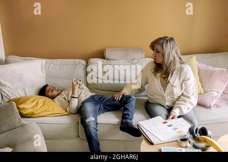 Autistic son lying on sofa by mother in living room Stock Photo