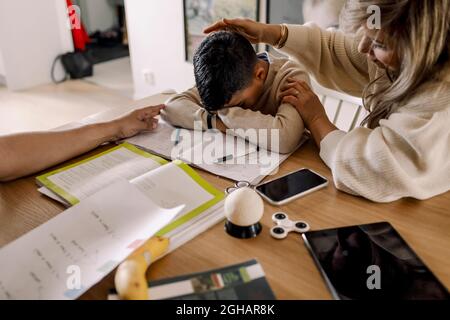 Mother sitting tired son at table in living room Stock Photo