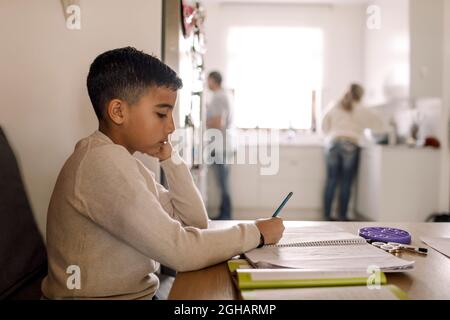Autistic boy writing in book over table at home Stock Photo