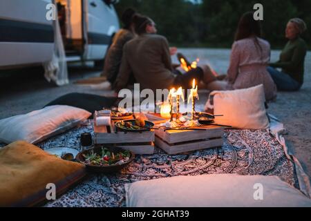 Female and male friends talking by camping van during vacation Stock Photo