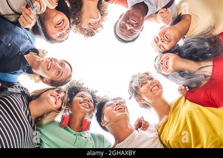 Low angle of a group of students are together, happy and smiling. Faces of young teenagers hugging. Stock Photo