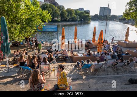 Berlin, Germany - July 30, 2021: People relax in beach bar at the Jannowitzbrucke by the Spree river