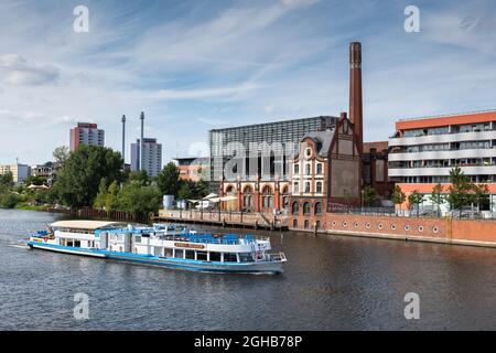 Berlin, Germany - July 30, 2021: Ernst Reuter passenger tour boat on River Spree and skyline with Radialsystem building