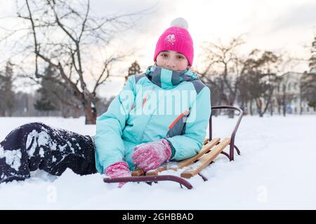 Teengae girl having fun playing with the sledge in the snow in winter. Stock Photo