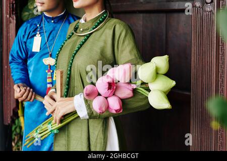 Bouquet of white and yellow lotus flowers in hands of bride standing next to her groom Stock Photo