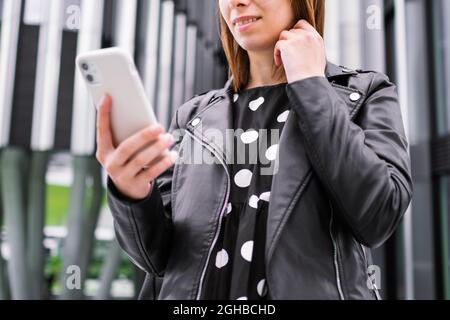 Modern business woman talking online using smartphone near the business center Stock Photo