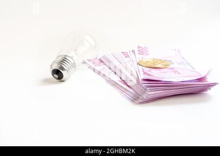 Light bulb Turkish lira banknotes and bitcoin isolated on white background. High electricity bill and living difficulties concept. Stock Photo