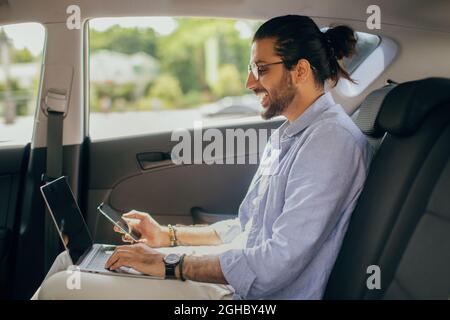 Stylish young middle-eastern guy independent contractor working in car Stock Photo