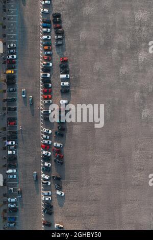 Different Cars are parked in parking spaces. Vertical shot of car parking lot near airport with copyspace. Aerial top view.