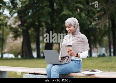 Smiling attractive muslim afro american lady student or business woman studying or working in city with coffee Stock Photo