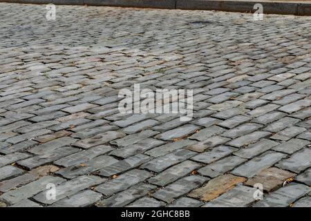 Low view of a gray stone block street seen from an oblique angle, transportation background with selective focus, horizontal aspect Stock Photo