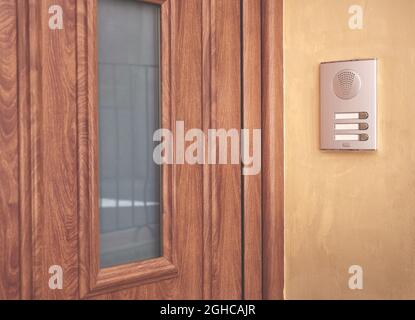 detail of a brown entrance door with intercom on stucco wall Stock Photo