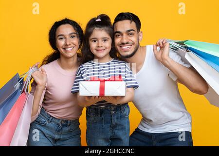 Portrait of happy middle-eastern family of three holding shopping bags and gift Stock Photo