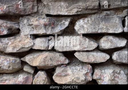 detail of a wall of irregular stones with little mortar Stock Photo