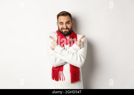 Winter holidays and shopping concept. Bearded man looking indecisive, asking for advice with choice, picking christmas gifts, pointing sideways Stock Photo