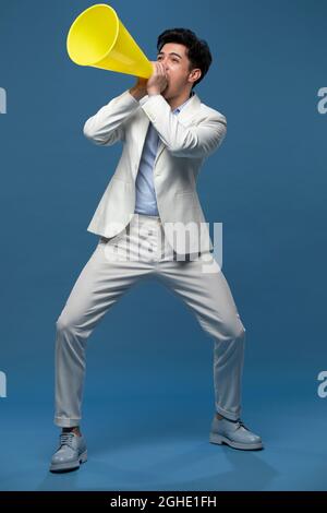 Studio shot of young man shouting through megaphone Stock Photo