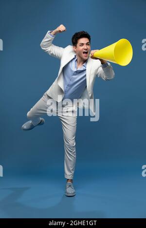 Studio shot of young man shouting through megaphone Stock Photo