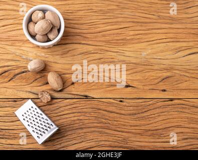 Nutmegs with grater over wodden table with copy space. Stock Photo