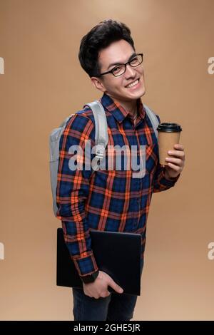 Young man holding a laptop and a cup of coffee Stock Photo
