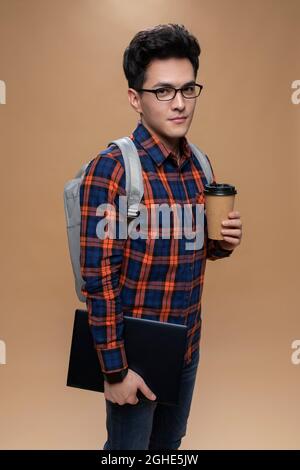 Young man holding a laptop and a cup of coffee Stock Photo