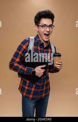 Young man holding a laptop and a cup of coffee Stock Photo