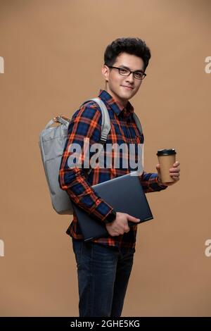 Young man holding a laptop and a cup of coffee Stock Photo