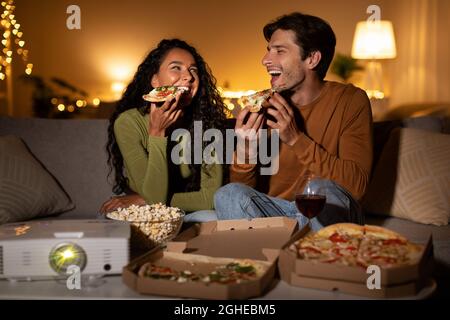 Couple Eating Pizza Watching Film Using Home Cinema Projector Indoor Stock Photo