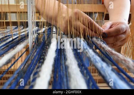 Closeup shot of a woman's hands weaving on a loom Stock Photo