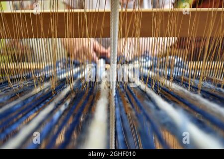 Closeup shot of a woman's hands weaving on a loom Stock Photo