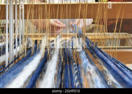 Closeup shot of a woman's hands weaving on a loom Stock Photo