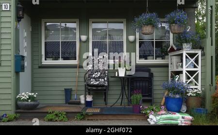 facade of a wooden house with ornate colored door and windows. Beautiful balcony with many pots and flowers in front. Tromso, Norway Stock Photo