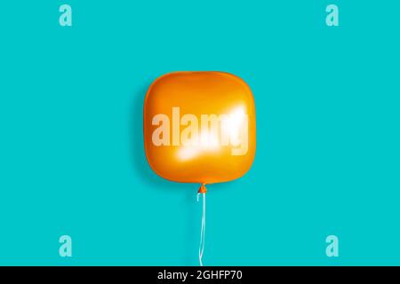 A square orange balloon on a pastel blue background. Innovation concept