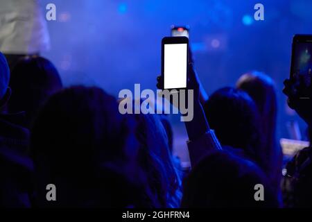Black silhouette of music fan with smartphone on dance floor filming video and taking pictures on popular edm musical festival in concert. Stock Photo