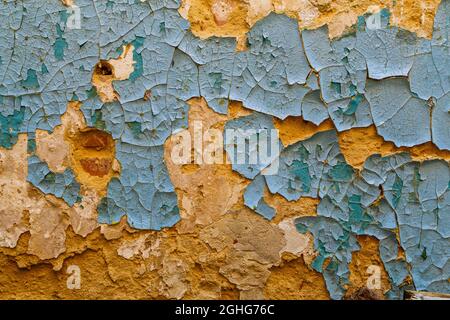 peeling blue paint on yellow sandy plaster wall - close-up full frame background and texture Stock Photo