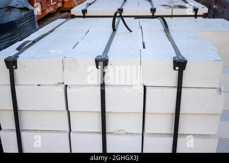 White silicate brick on pallets in a warehouse of building materials. Stock Photo