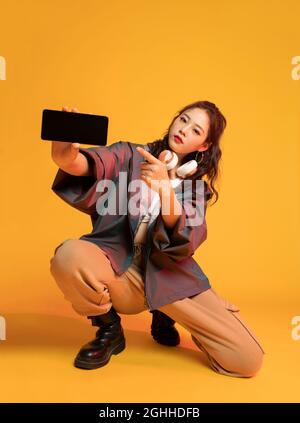 Studio shot of fashionable young woman holding a smart phone Stock Photo