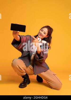 Studio shot of fashionable young woman holding a smart phone Stock Photo